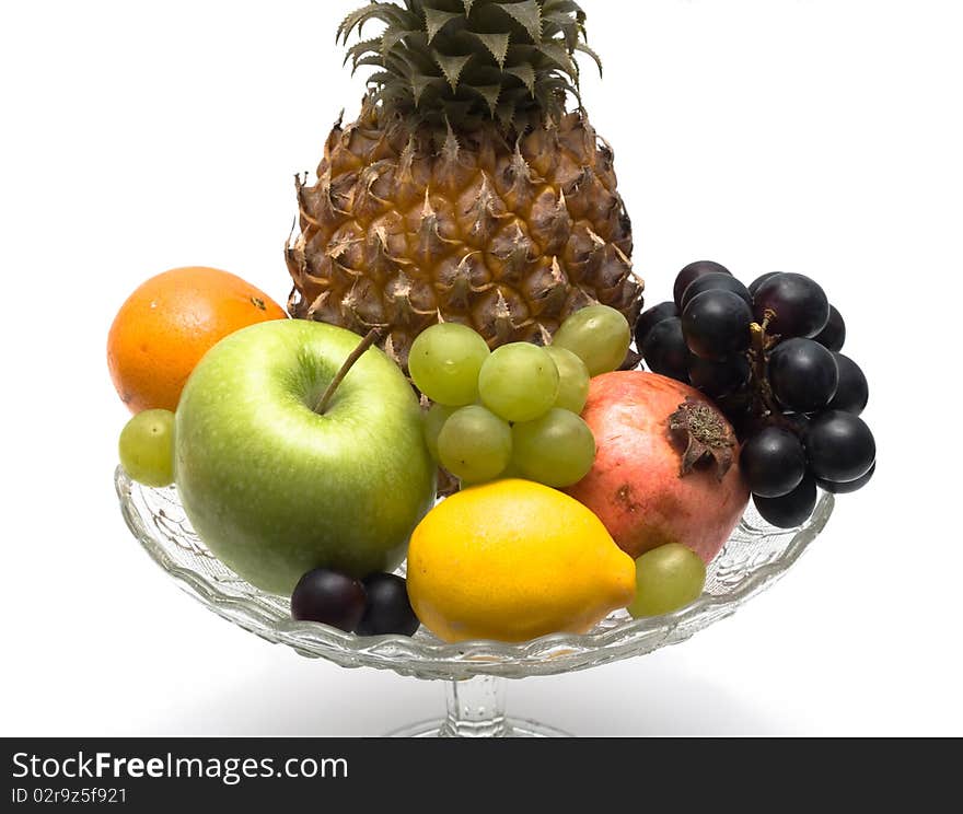 Group of different fruits in a glass vase on a white background