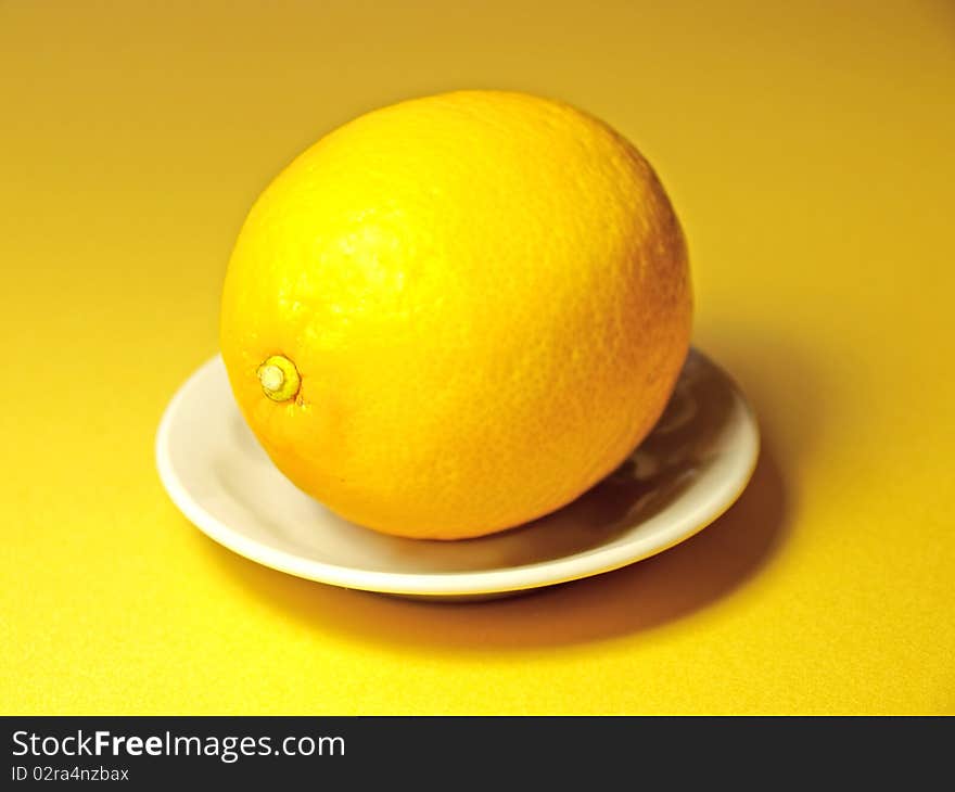 Lemon with a small plate on yellow background