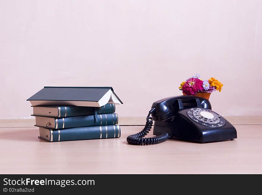 Stack of books with vintage telephone and flowers