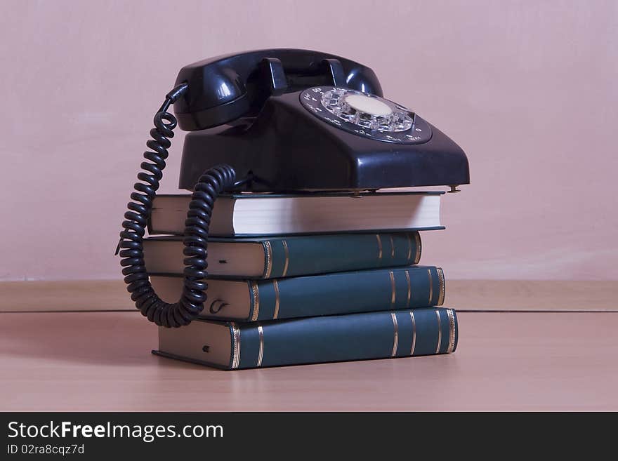 Small stack of books with vintage telephone on top