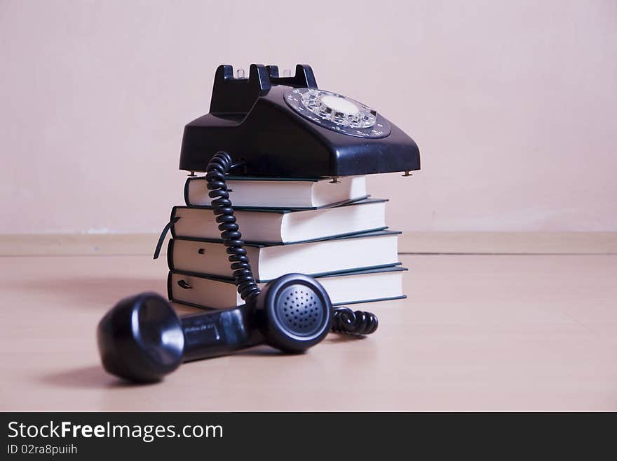 Stack of books with vintage telephone on top