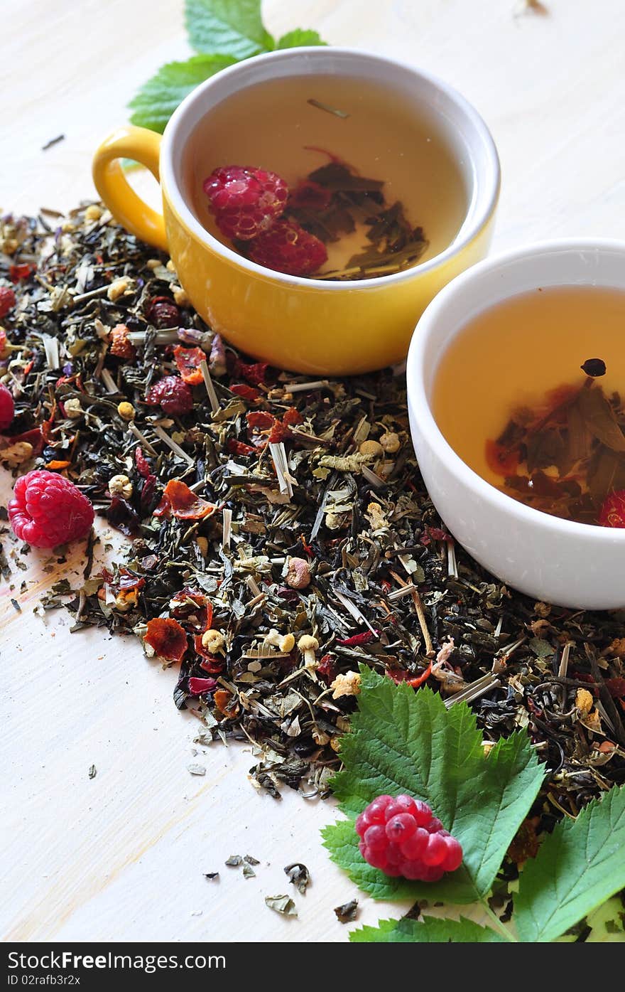 Two cups herbal tea is brewed in which,  alongside dry tea and berries of raspberry