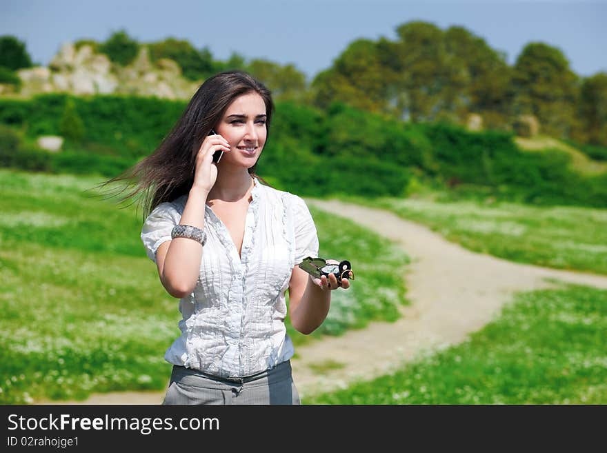 Portrait of young pretty woman speaking on phone with compass in hand