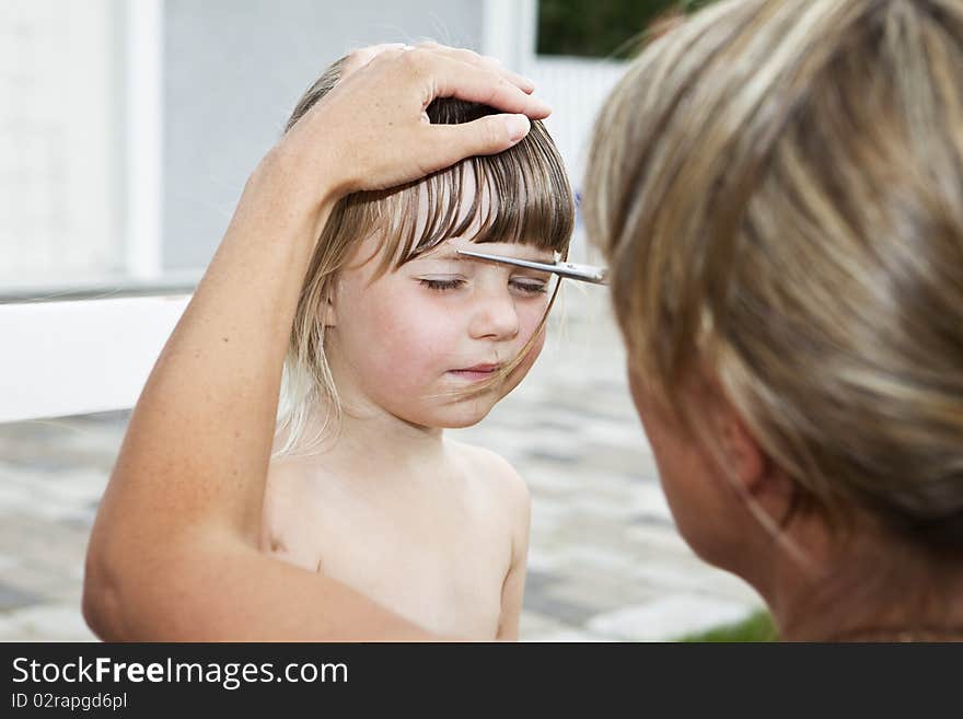 Woman cutting young girls hair outdoor. Woman cutting young girls hair outdoor