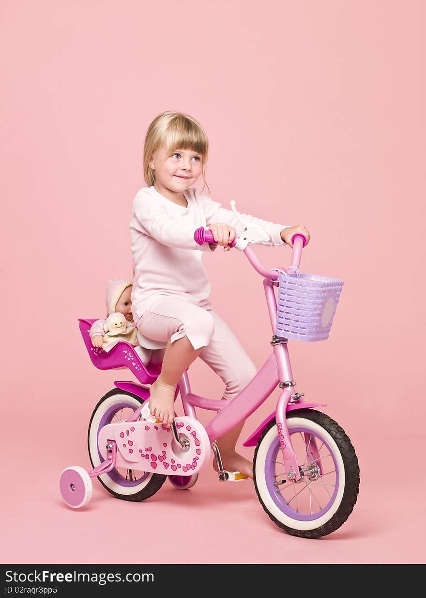 Young girl on her bike towards pink background