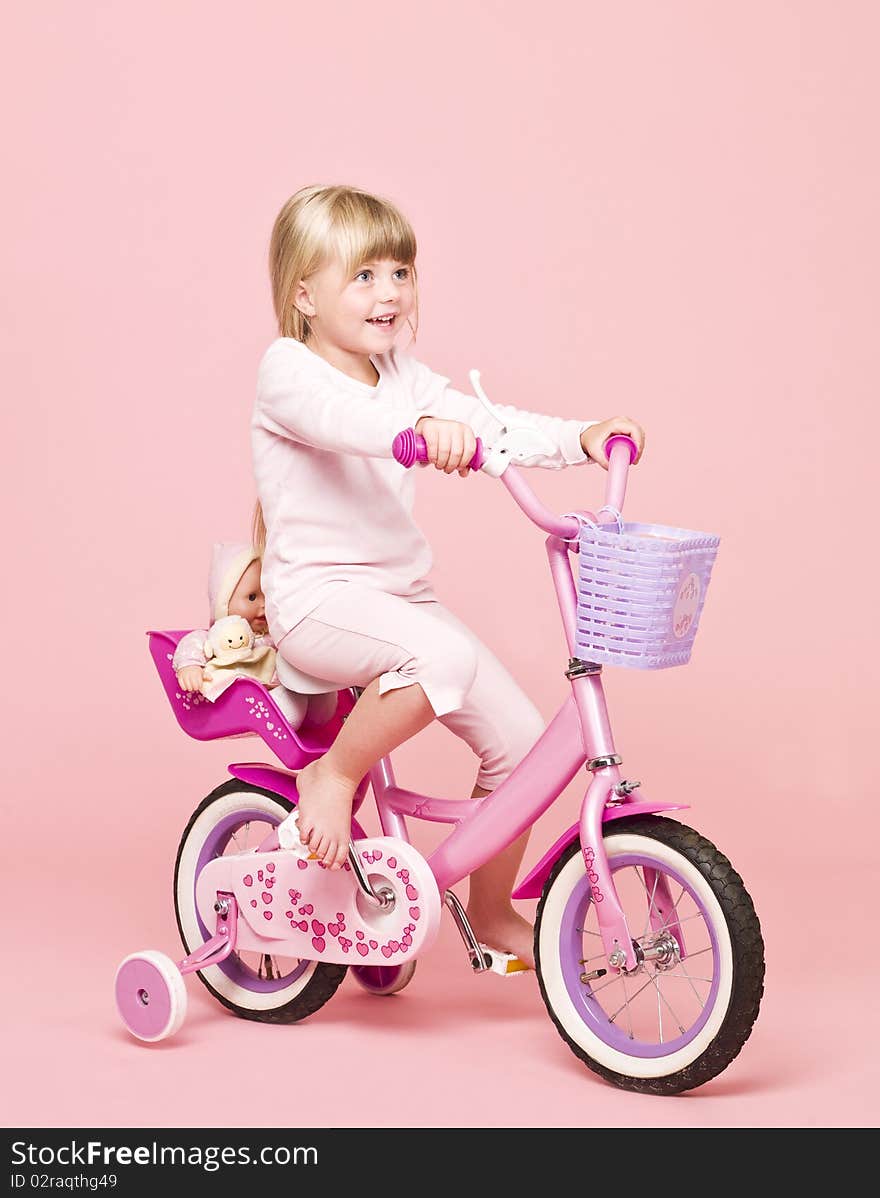 Young girl on her bike towards pink background