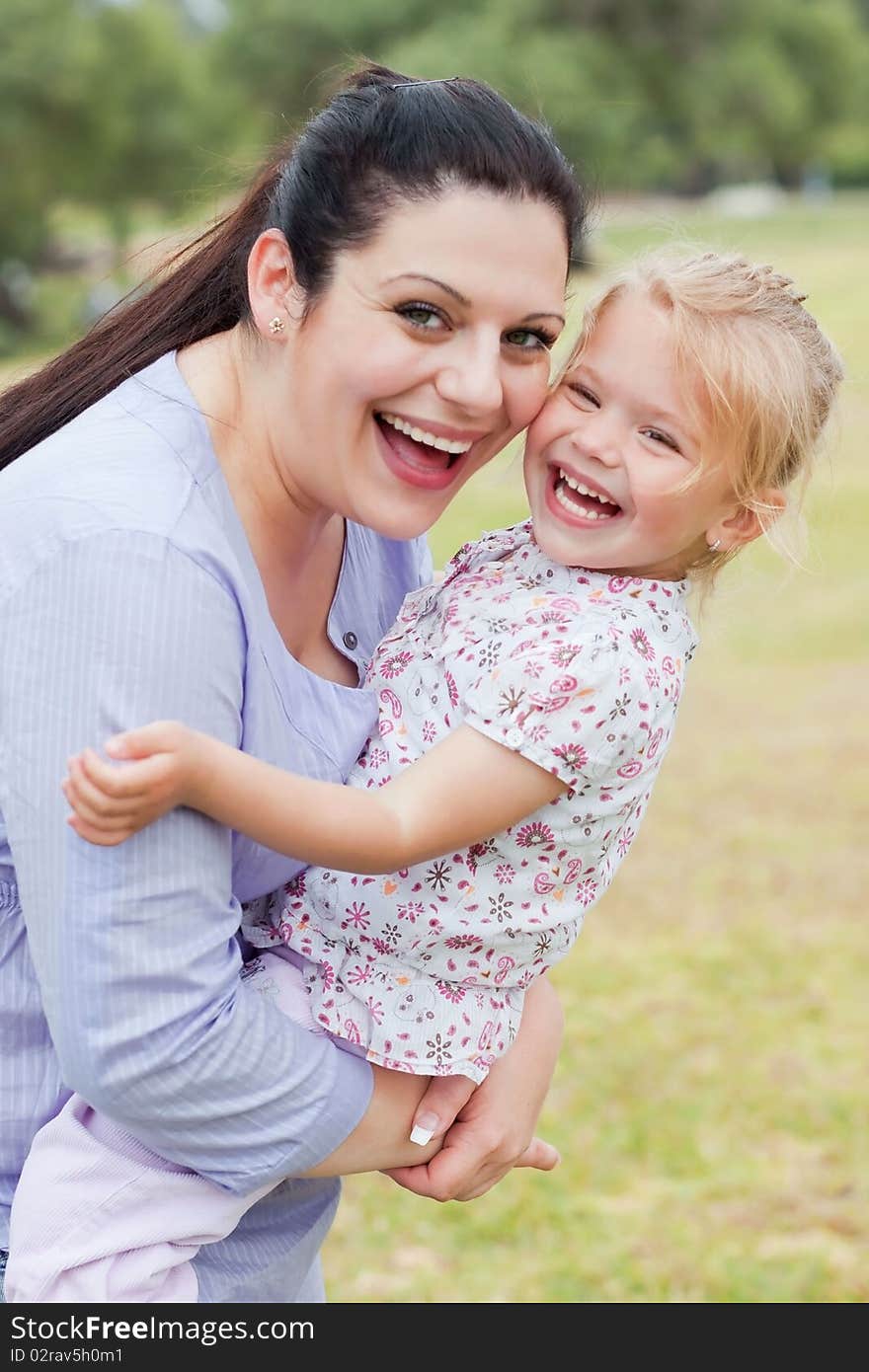 Curious mother carrying her daughter with big smile at the park