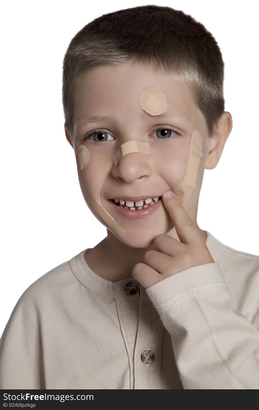 Portrait of young boy with band aids on face looking at camera and smiling, studio shot isolated on white background. Portrait of young boy with band aids on face looking at camera and smiling, studio shot isolated on white background