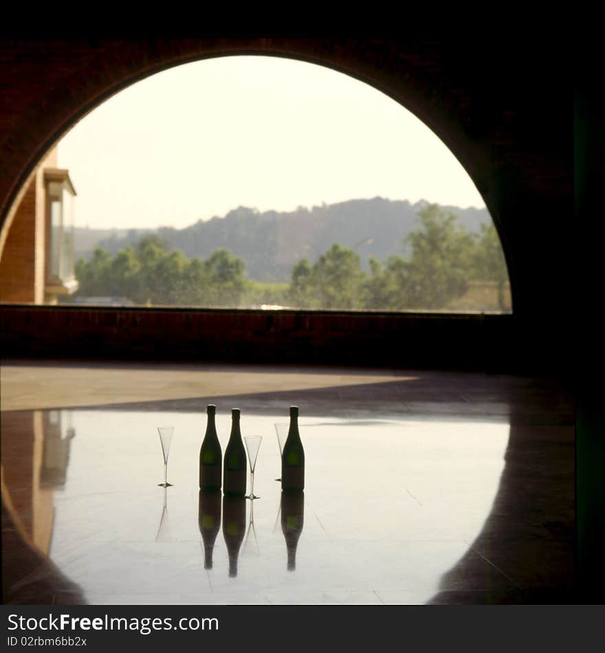 Three bottles of champagne and glasses standing in sun floated windows half.