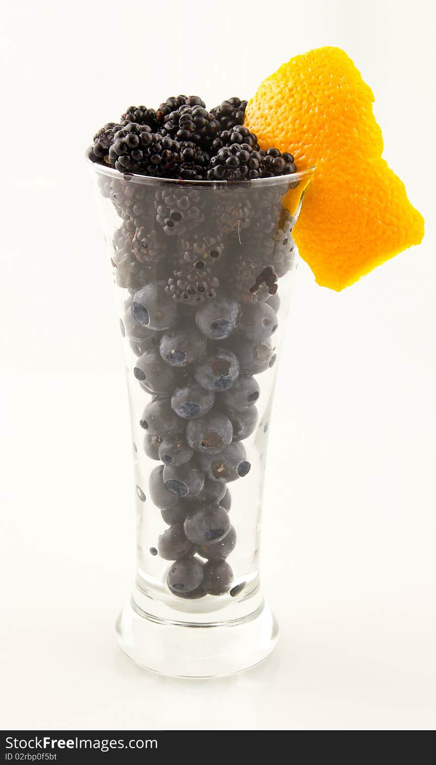 This is an image of blueberries and blackberries in a tall glass with a twist. This is an image of blueberries and blackberries in a tall glass with a twist.