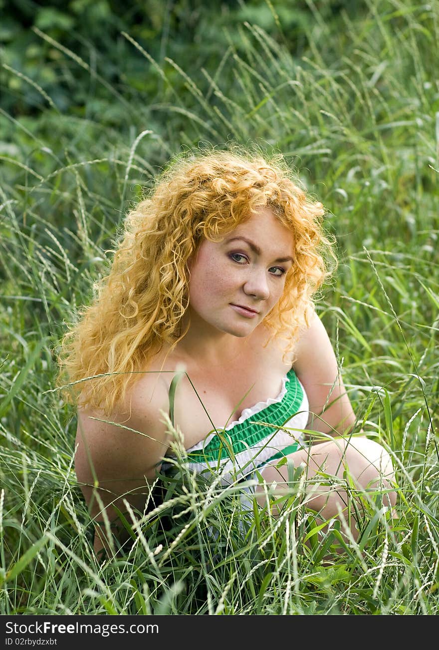 Young red-haired girl sits in the grass, Ukraine