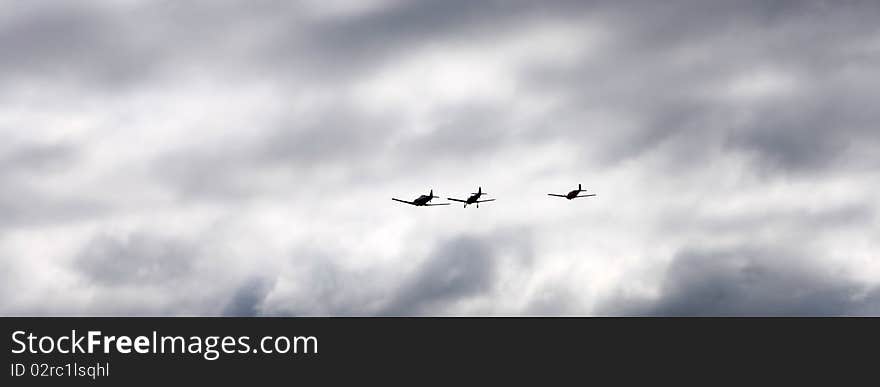 Silhouettes of three airplanes flying into dramatic clouds