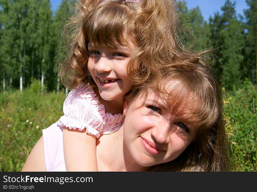 The laughing beautiful girl embraces the woman in the summer in park. The laughing beautiful girl embraces the woman in the summer in park