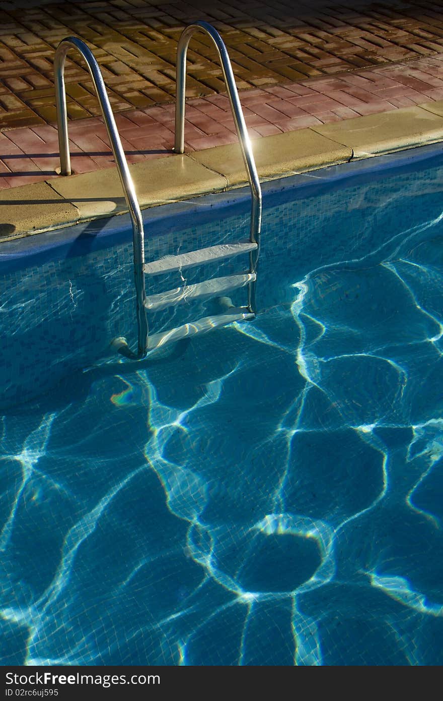 Rails of steps glint in the sunshine at the outdoor holiday pool. Rails of steps glint in the sunshine at the outdoor holiday pool