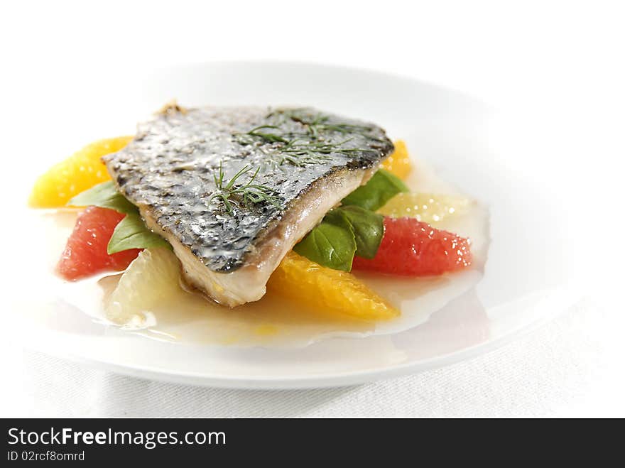 Delicious fried fish fillet with orange, grapefruit, lemon and fresh basil