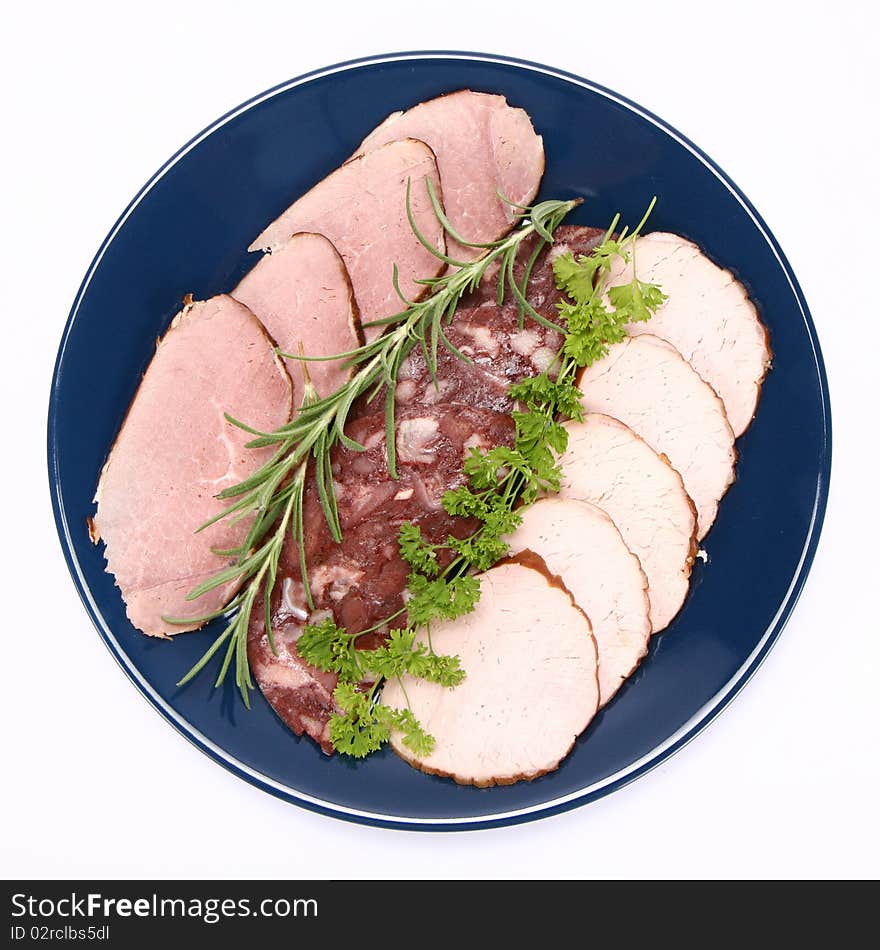 Plate of assorted cold cuts (ham, sirloin, headcheese) decorated with rosemary and parsley