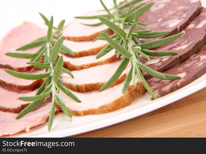 Plate of assorted cold cuts (ham, sirloin, headcheese) decorated with rosemary