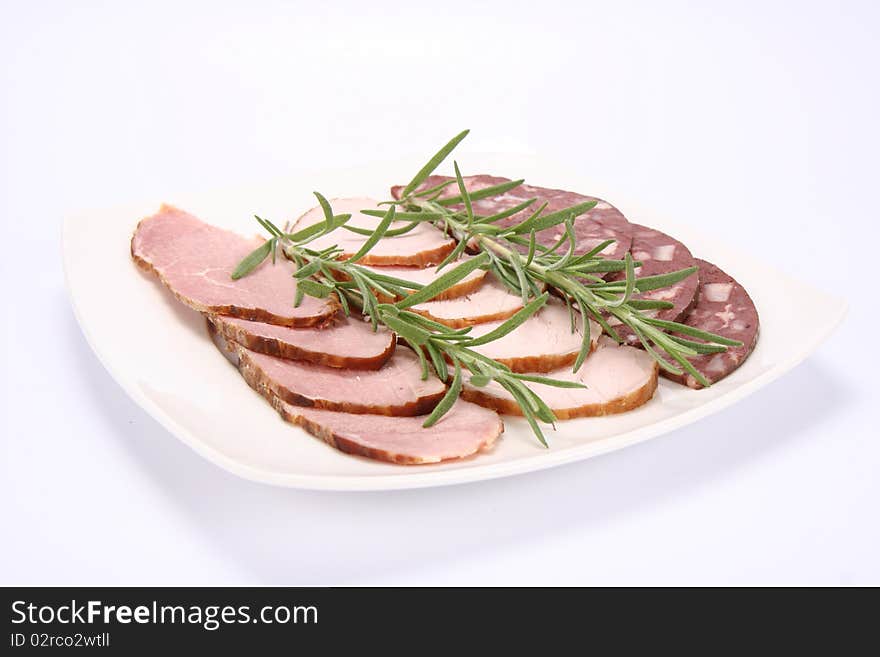 Plate of assorted cold cuts (ham, sirloin, headcheese) decorated with rosemary