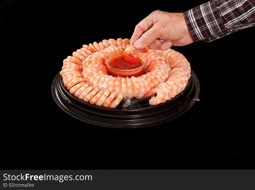 Male hand dipping a shrimp in cocktail sauce.
Black background. Male hand dipping a shrimp in cocktail sauce.
Black background.