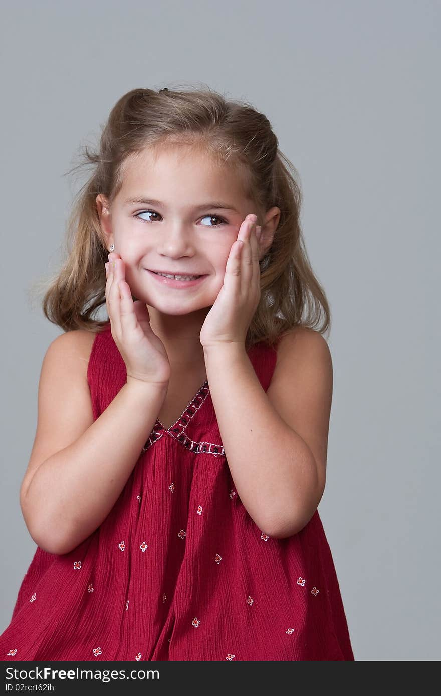 Pretty Little girl smiling with hands to face after being caught doing a mischievous deed. Pretty Little girl smiling with hands to face after being caught doing a mischievous deed.