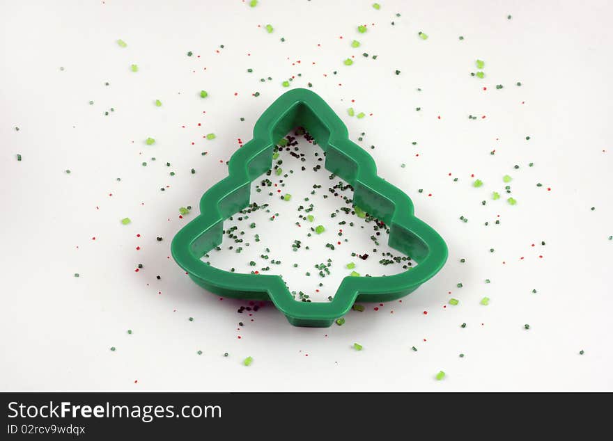 Christmas tree cookie cutter with red and green sprinkles laid out on a white background. Christmas tree cookie cutter with red and green sprinkles laid out on a white background