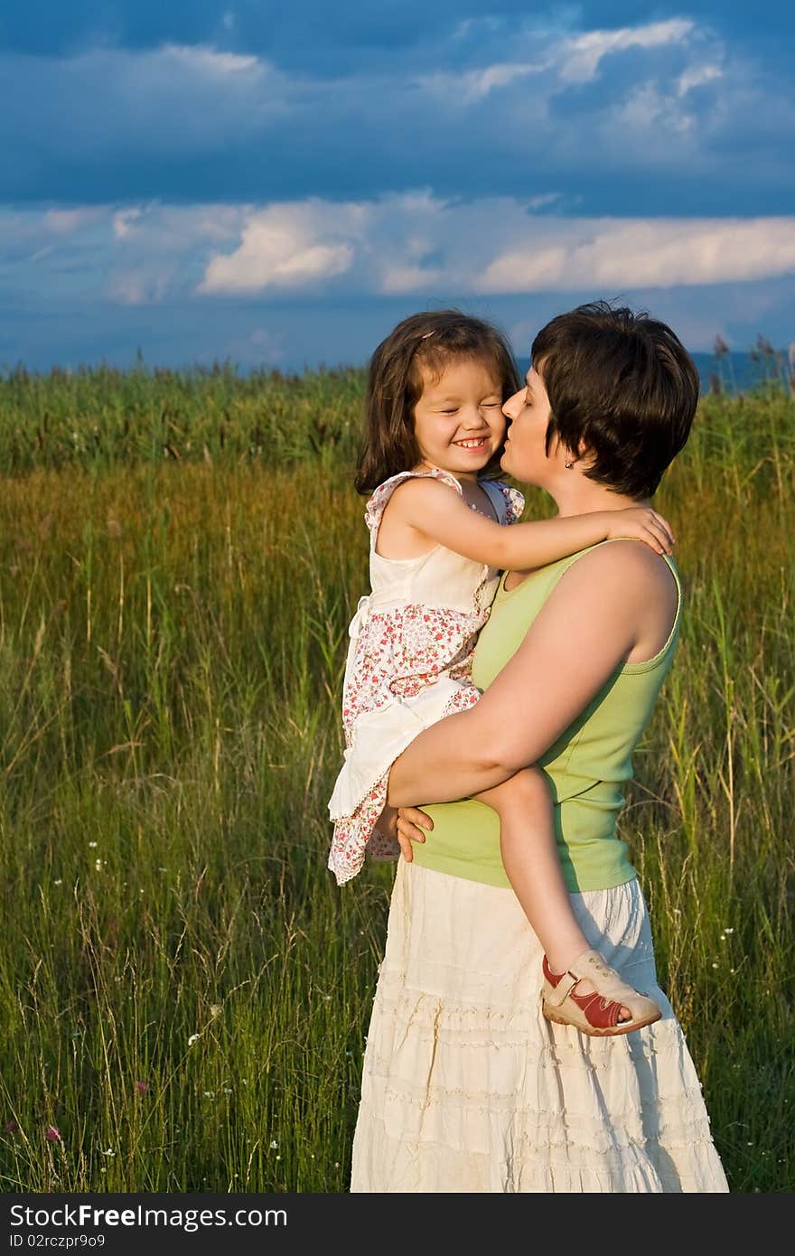 Beautiful young woman kissing her happy daughter. Beautiful young woman kissing her happy daughter