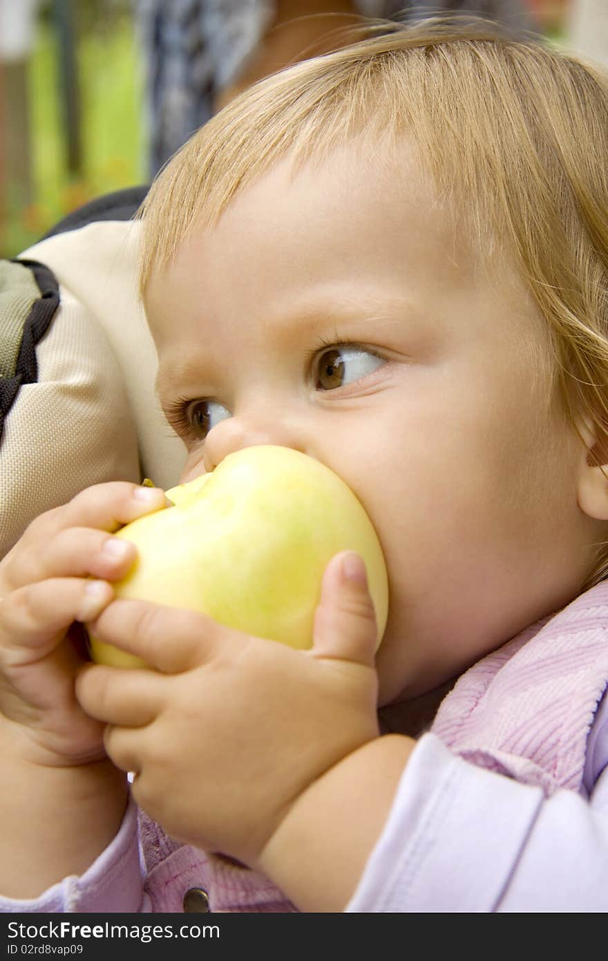 Small child bites the big apple and holds its two hands