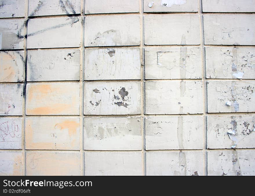 Dirty white brick wall. It can be seen fragments of ads and inscriptions. Dirty white brick wall. It can be seen fragments of ads and inscriptions.