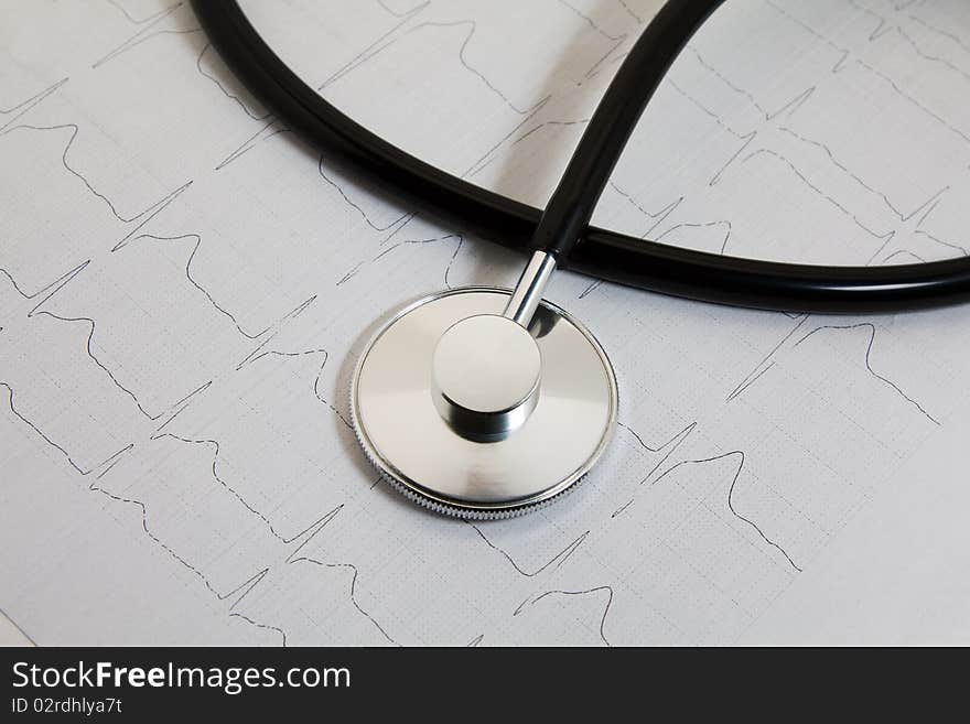 The stethoscope lying on a paper with the cardiogramme of heart