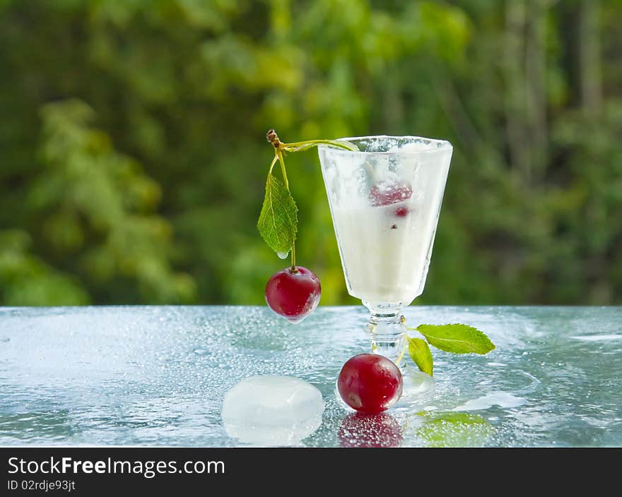 A small cup of cold cream and cherries. A small cup of cold cream and cherries