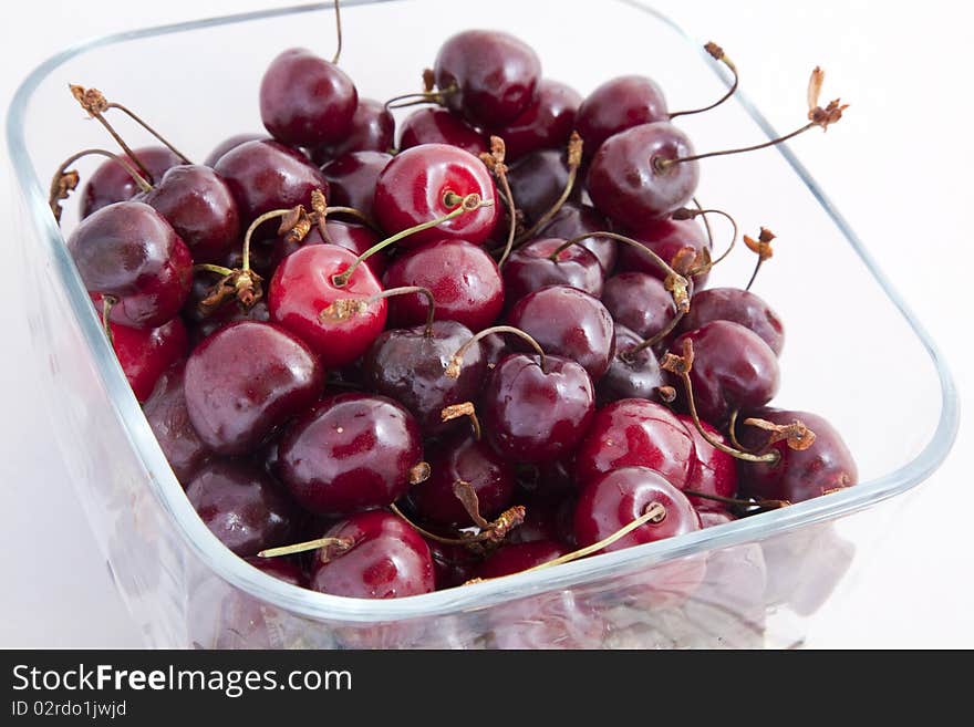 A white bowl of cherries on a white background.