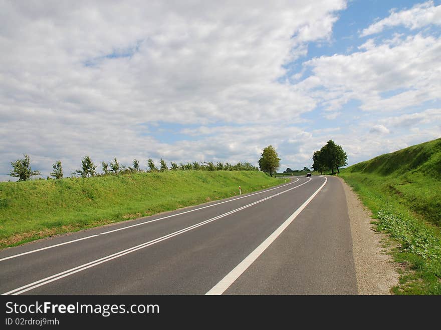 A deserted country road running through some green fields