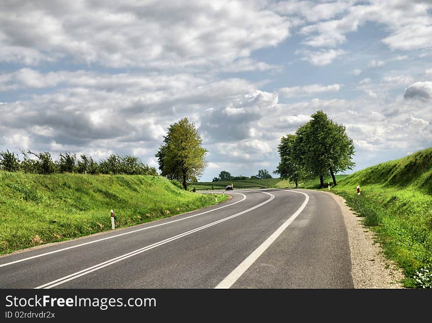 A deserted country road running through some green fields