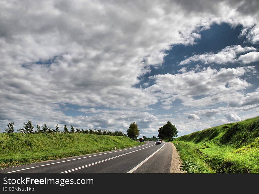 A deserted country road running through some green fields