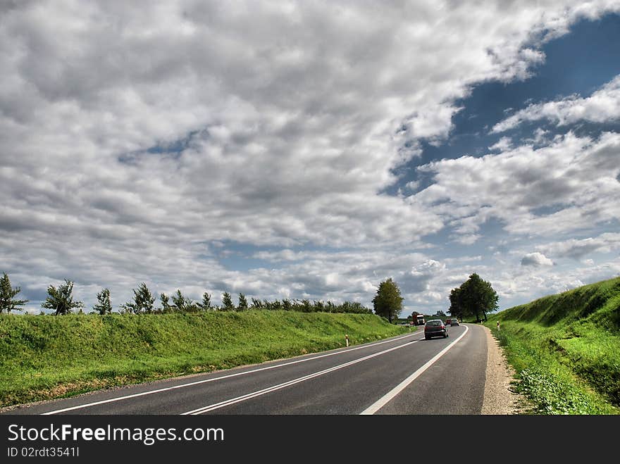 A deserted country road running through some green fields