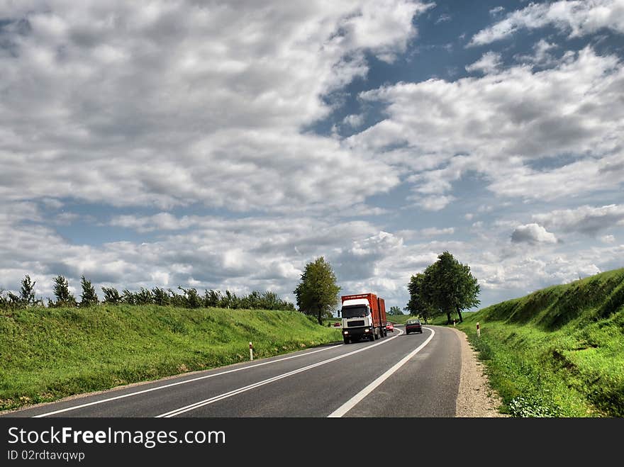 A deserted country road running through some green fields