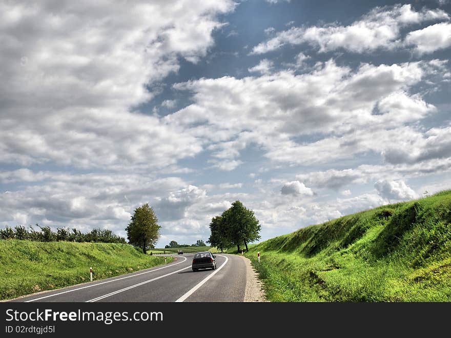 A deserted country road running through some green fields