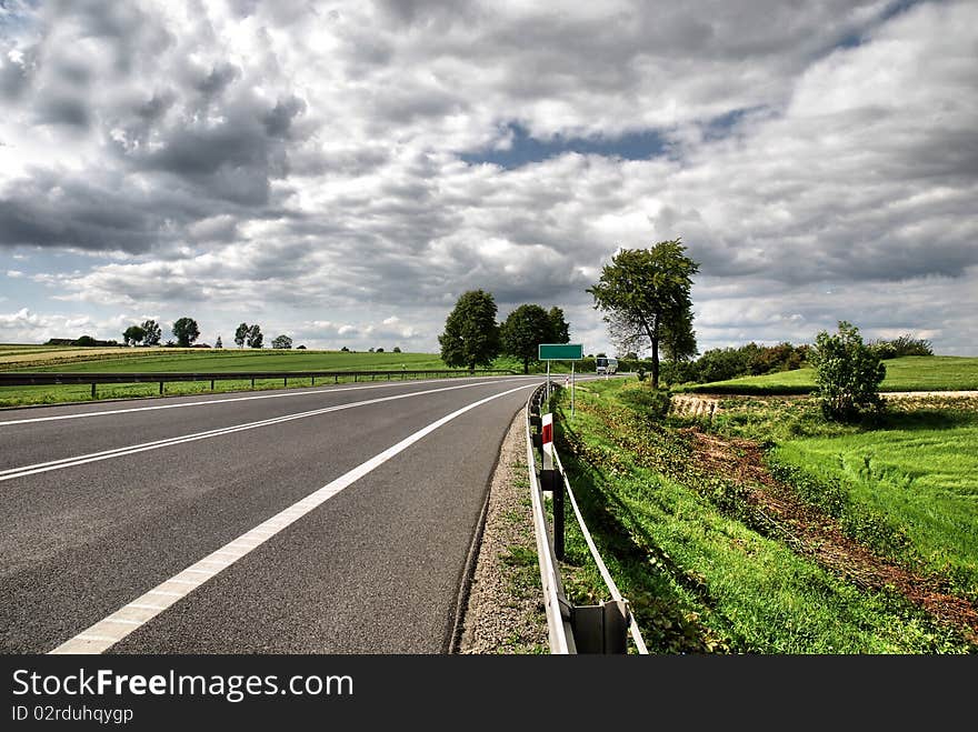 A deserted country road running through some green fields