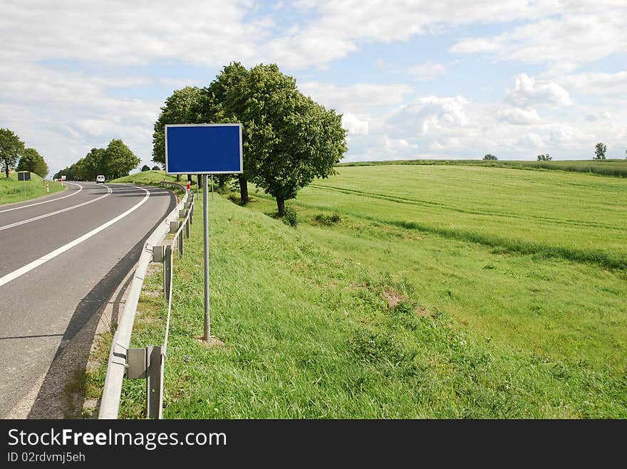 A deserted country road running through some green fields