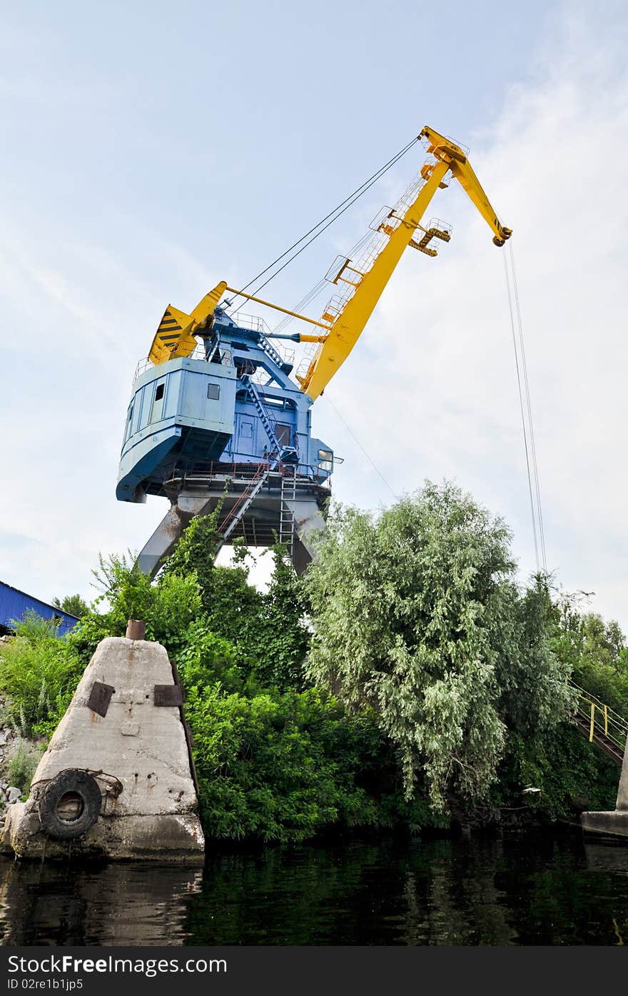 Crane near the mine on the river against blue sky. Crane near the mine on the river against blue sky