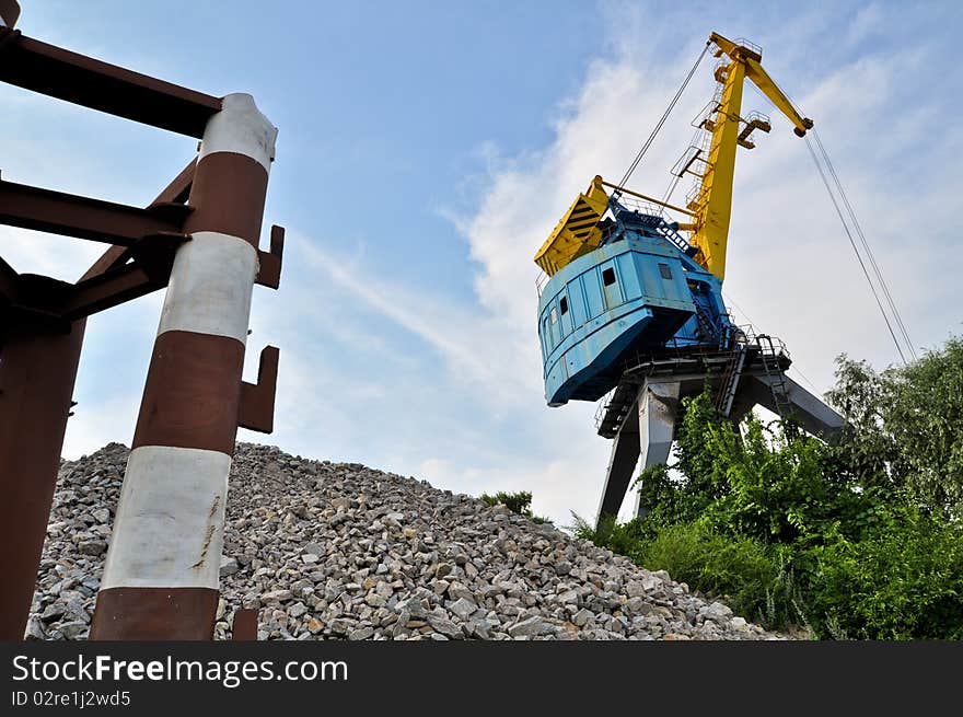 Crane near the mine on the river against blue sky. Crane near the mine on the river against blue sky