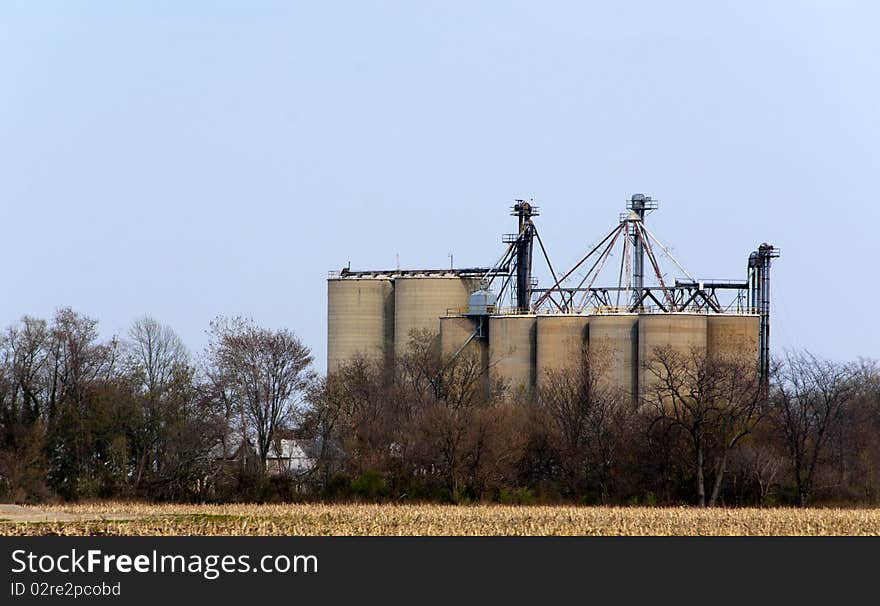 A grainery located on farmland with trees, grass and blue sky. A grainery located on farmland with trees, grass and blue sky.