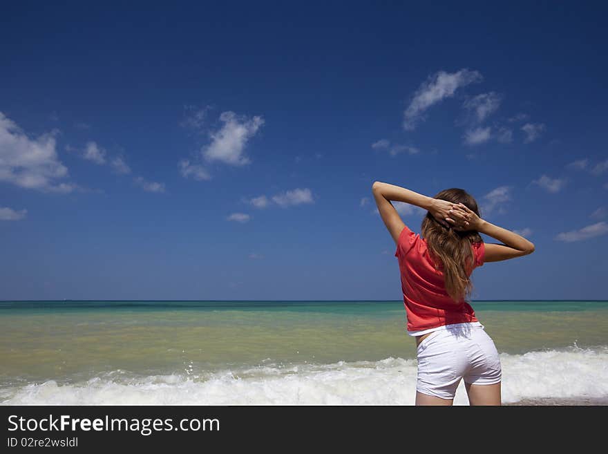 Young female looking at sea with her hands up getting a breath of sea air