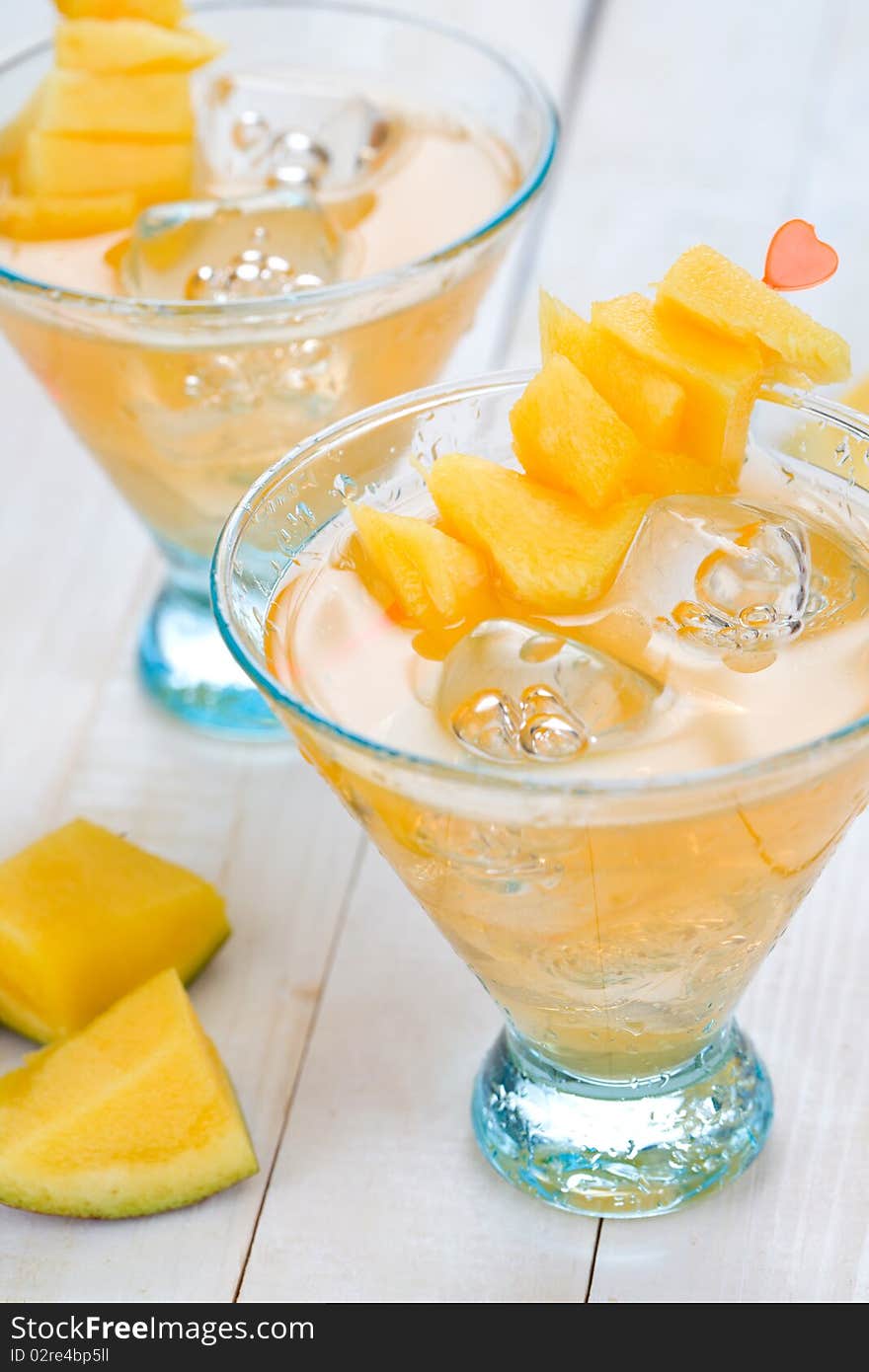 Cocktail with mango fruit on wooden table top