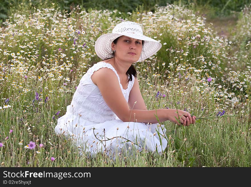 Lady in white dress and hat on a field with camomiles