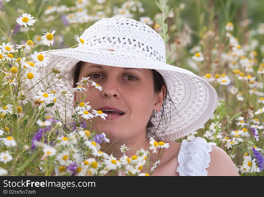 Lady in white dress and hat on a field with camomiles. Lady in white dress and hat on a field with camomiles