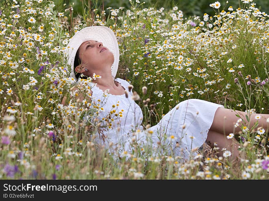 Lady in white dress and hat on a field with camomiles