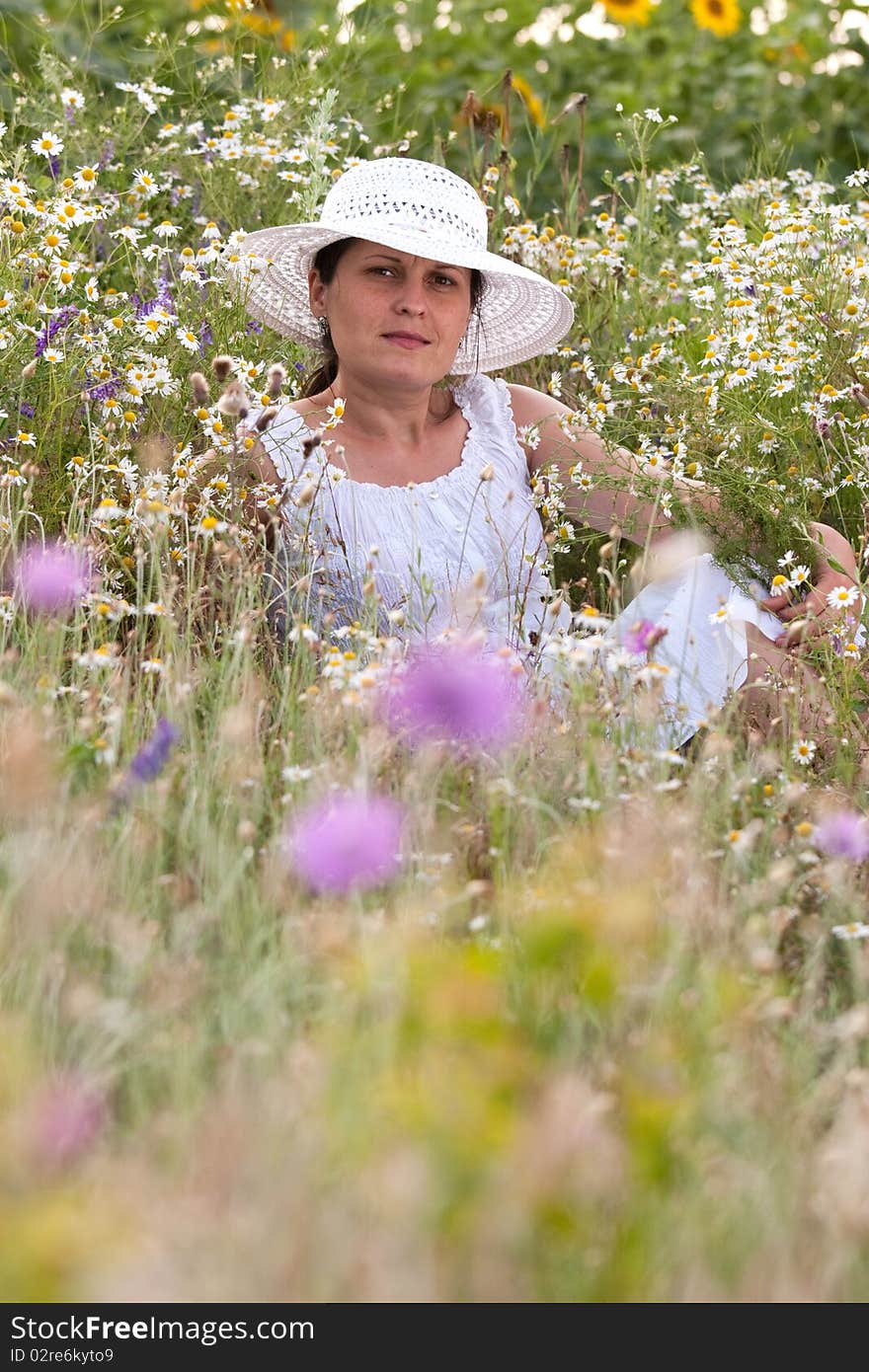 Lady in white dress and hat on a field with camomiles