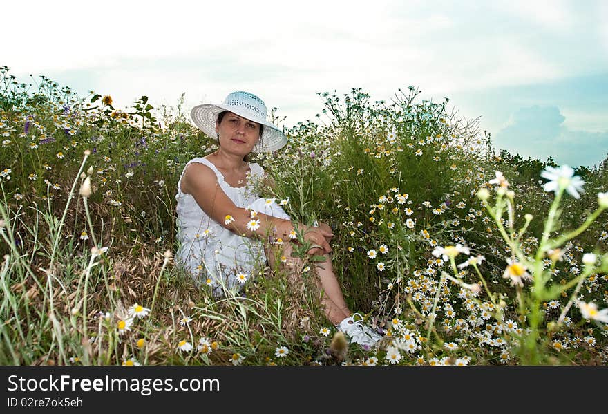 Lady in white dress and hat on a field with camomiles. Lady in white dress and hat on a field with camomiles