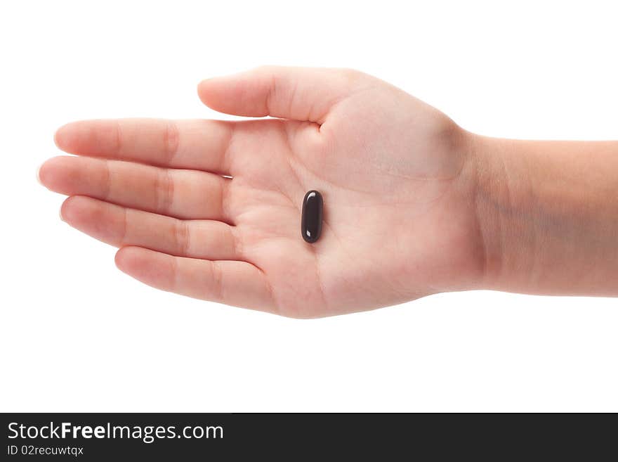 Female hand holding a black capsule, isolated on white